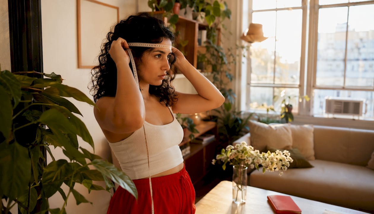 Person measuring head circumference with tape