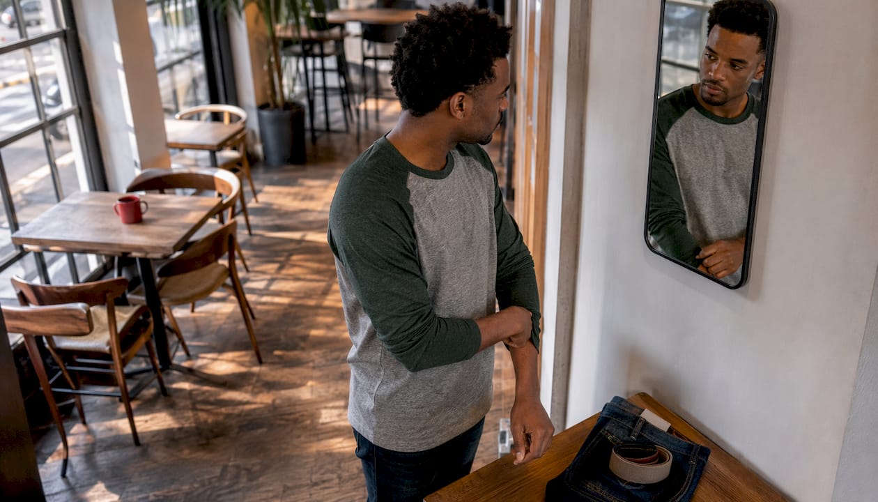 Man fitting raglan shirt in mirror